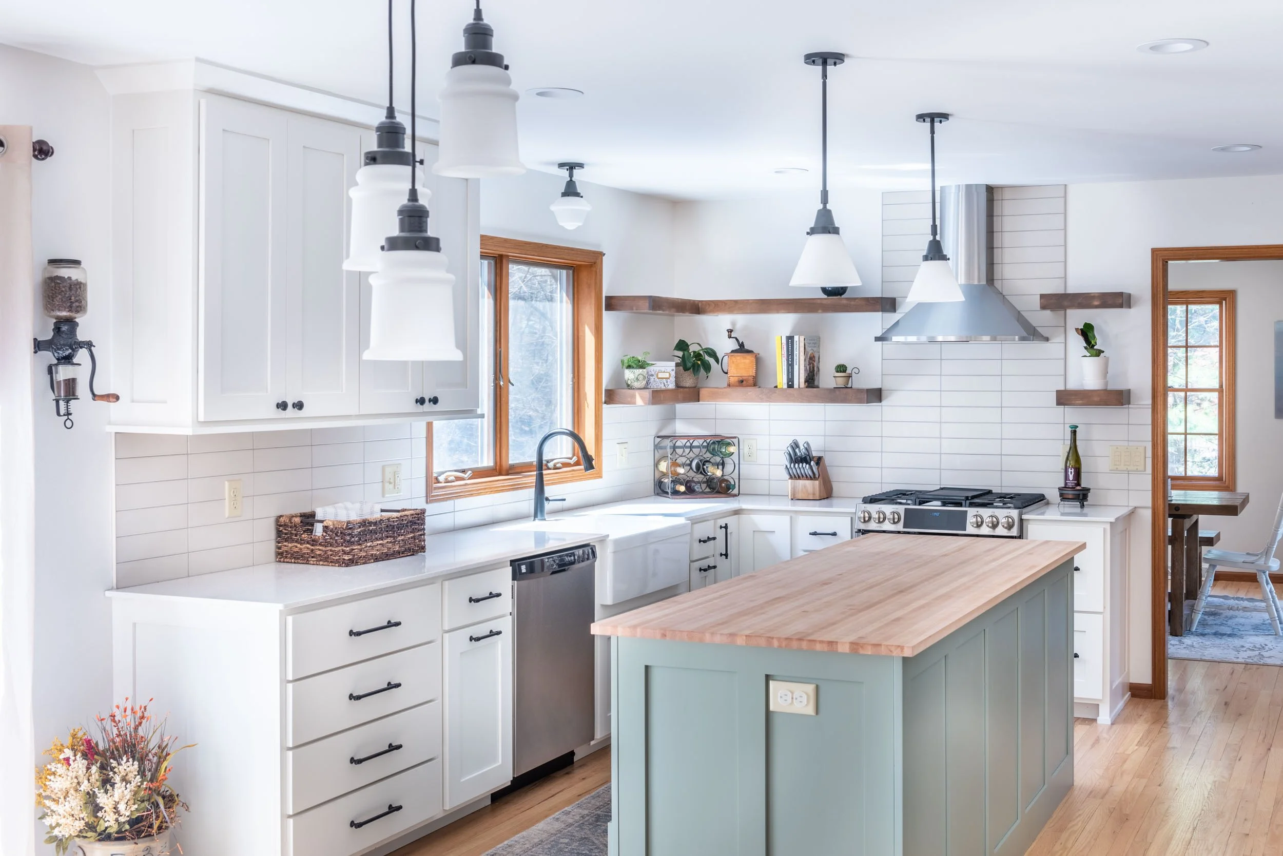 Bright remodeled kitchen with white cabinets, tile backsplash, pendant lights, and a center island